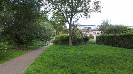 Links voetpad langs grasveld naar bruggetje en woonwijk Brugakker
