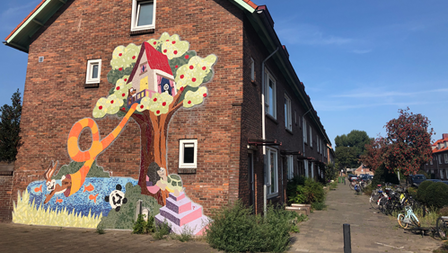 Beschilderde zijkant van een woning met daarop boomhut in een boom en spelende dieren